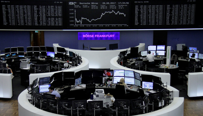 Traders work in front of the German share price index, DAX board, at the stock exchange in Frankfurt