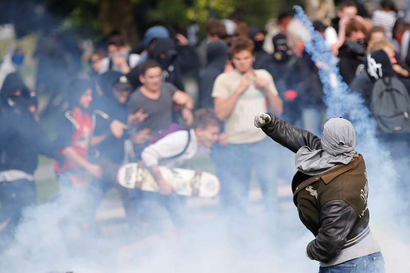 A demonstrator throws back a tear gas during a national strike and protest against the government's labour reforms in Nantes