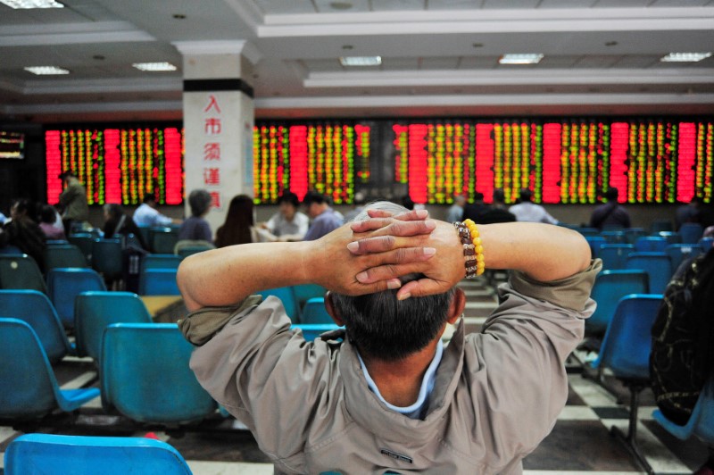 Investor looks at electronic board showing stock information at brokerage house in Nanjing