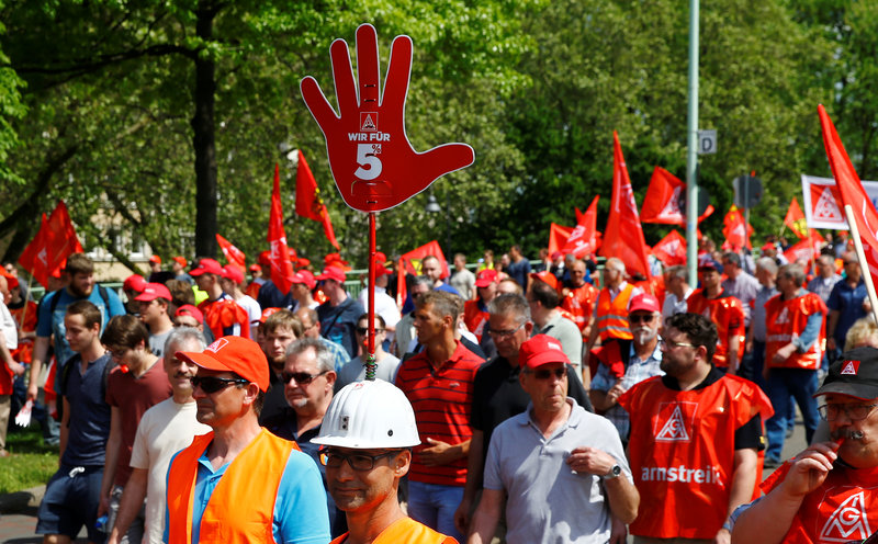 FILE PHOTO: A worker has a sign on helmet with text 'We are for 5%' as steel workers of Germany's IG Metall union protest for higher wages in Cologne