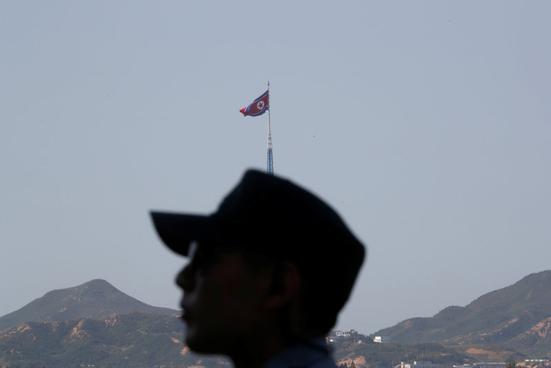 A South Korean soldier stands guard as a North Korean flag flutters on top of a tower at the propaganda village of Gijungdong in North Korea in this