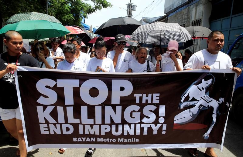 FILE PHOTO: Relatives and loved ones of Leover Miranda hold a streamer calling to stop the continuing rise of killings uring a funeral march at the north cemetery in metro Manila