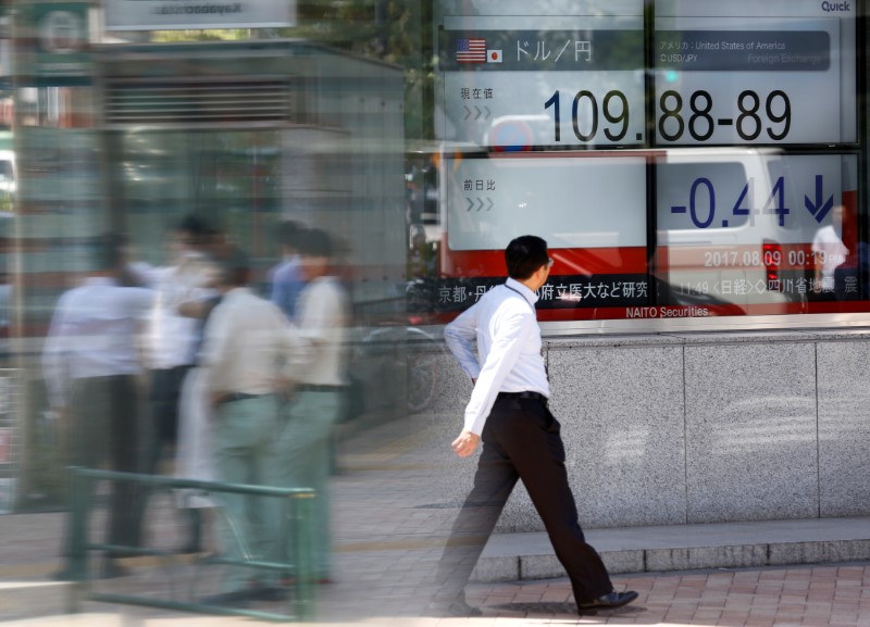 People walk past an electronic board showing exchange rate between Japanese Yen and U.S. Dollar outside a brokerage at a business district in Tokyo