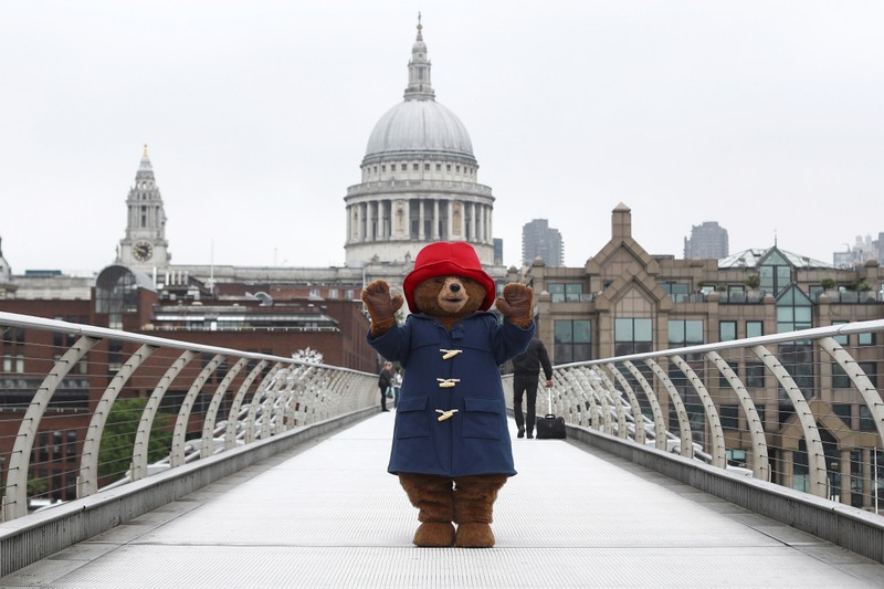 A performer wearing a Paddington Bear costume poses for photographers in front of St Paul's Cathedral in London
