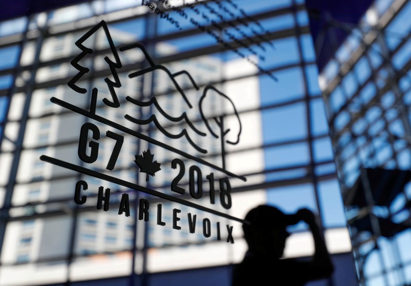 A man walks past the Charevoix G7 logo at the main press center ahead of G7 Summit in Quebec