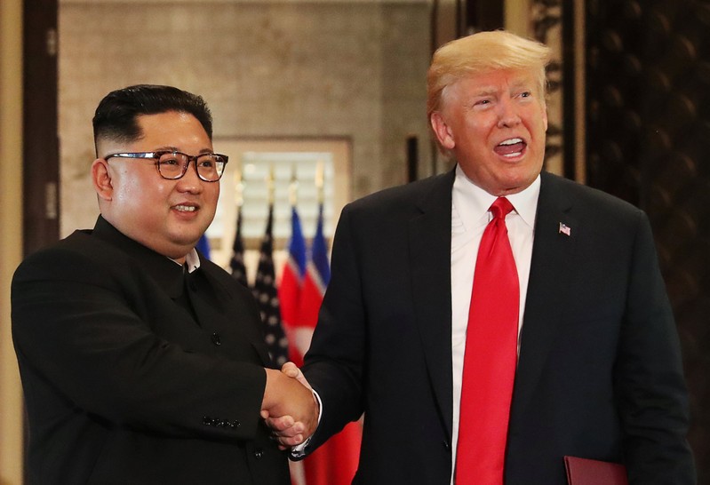 U.S. President Donald Trump and North Korea's leader Kim Jong Un shake hands after signing documents during a summit at the Capella Hotel on the resort island of Sentosa, Singapore