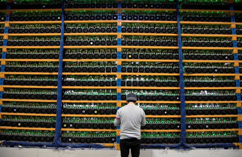 FILE PHOTO: A worker checks the fans on miners at the cryptocurrency farming operation Bitfarms in Farnham Quebec