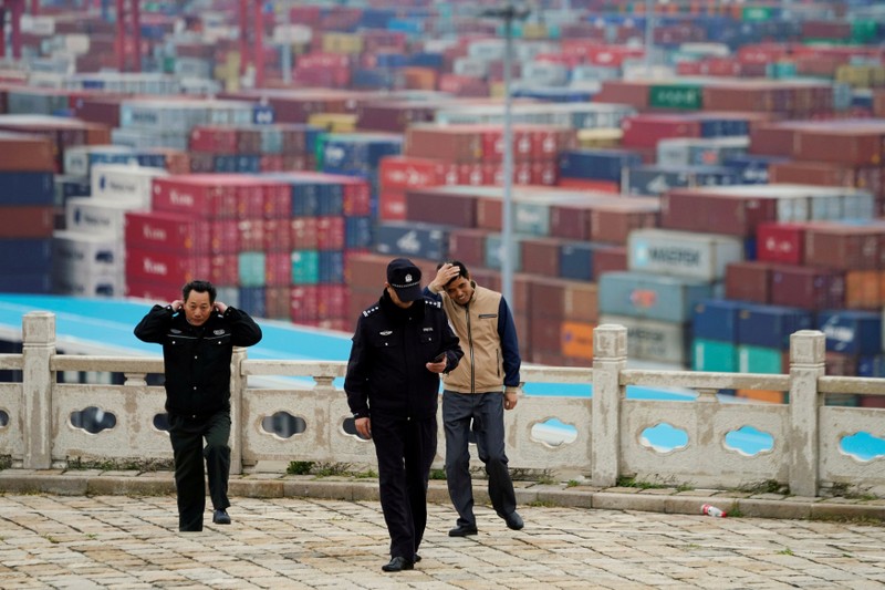 FILE PHOTO: Security guards walk in front of containers at the Yangshan Deep Water Port in Shanghai