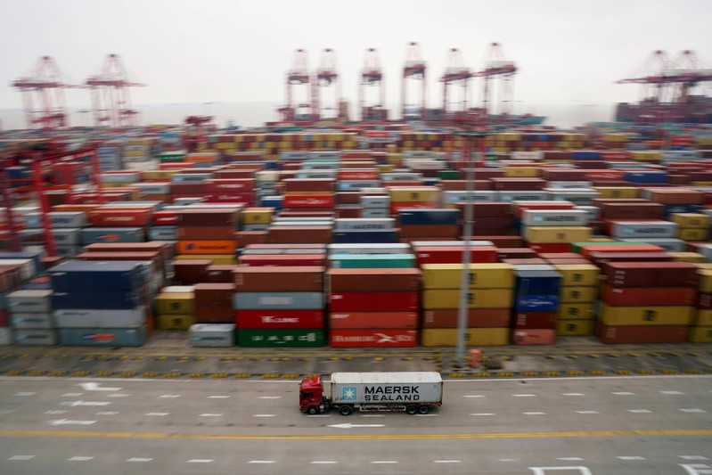 FILE PHOTO: A container truck moves past containers at the Yangshan Deep Water Port in Shanghai