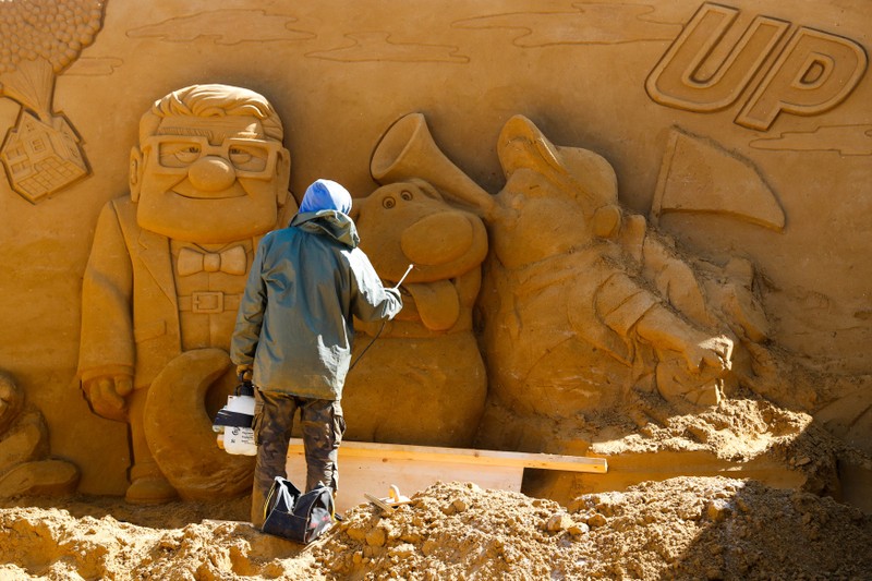 A sand carver works on a sculpture during the Sand Sculpture Festival