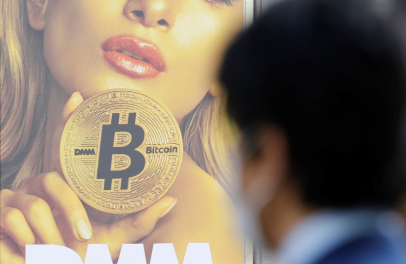 FILE PHOTO: A man stands near an advertisement of a cryptocurrency exchange in Tokyo