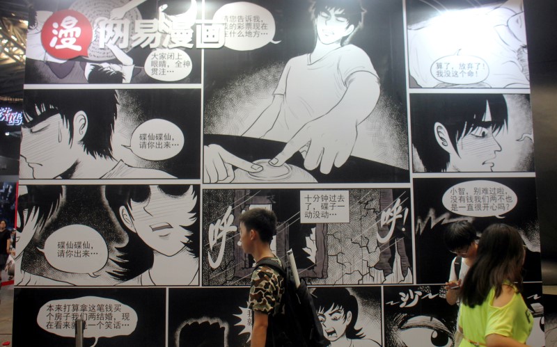 People walk past a booth of NetEase Comics at the CCG Expo in Shanghai