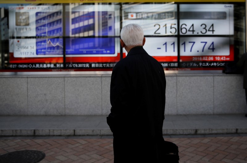 A man looks at an electronic board showing Japan's Nikkei average outside a brokerage in Tokyo