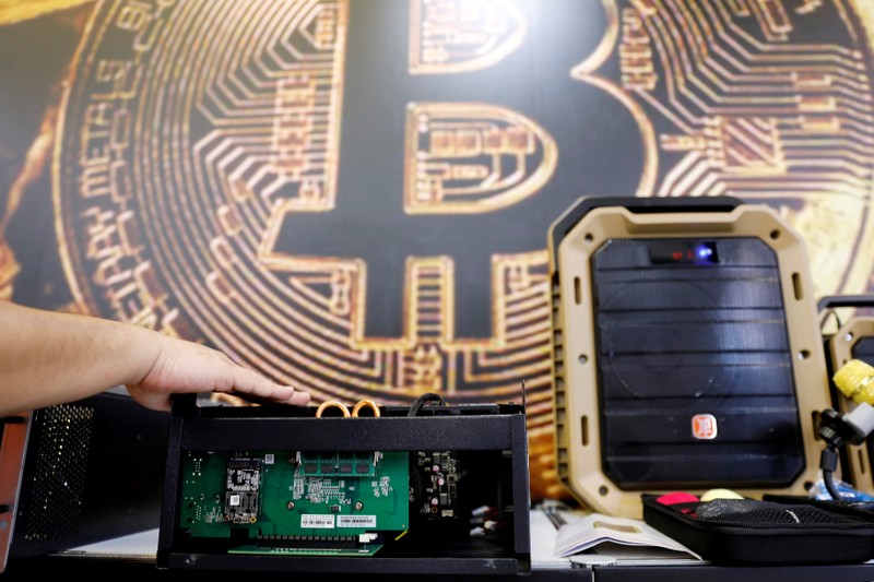A cryptocurrency mining computer is seen in front of bitcoin logo during the annual Computex computer exhibition in Taipei