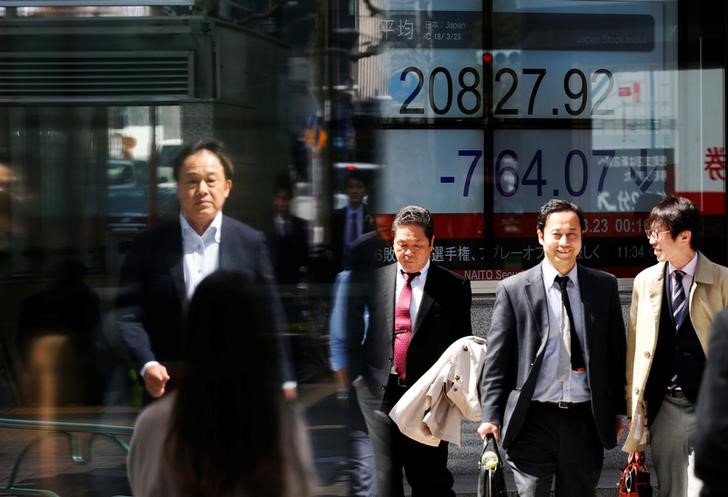 People walk past an electronic board showing Japan's Nikkei average outside a brokerage in Tokyo