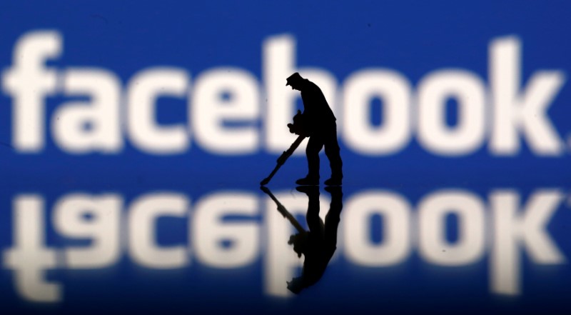 A figurine is seen in front of the Facebook logo in this illustration