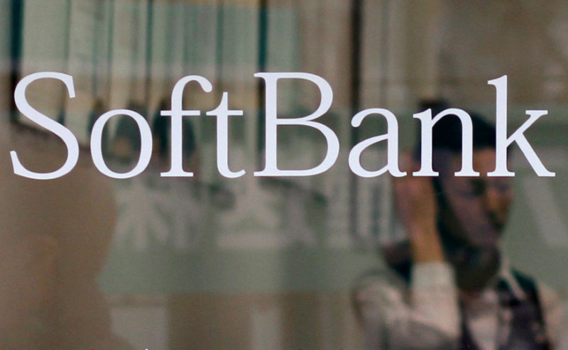 FILE PHOTO: An employee works behind a logo of Softbank Corp at its branch in Tokyo
