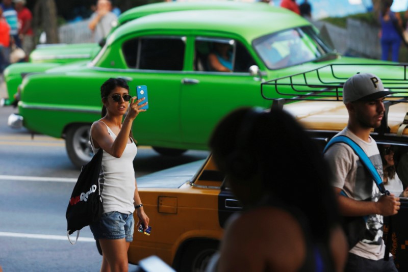 A woman uses the internet on her mobile phone at a hotspot in Havana, Cuba