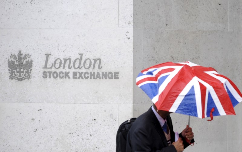 FILE PHOTO: A worker shelters from the rain as he passes the London Stock Exchange in the City of London