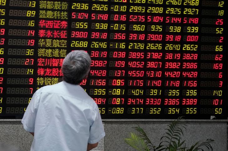 A man looks at an electronic board showing stock information at a brokerage house in Shanghai, China