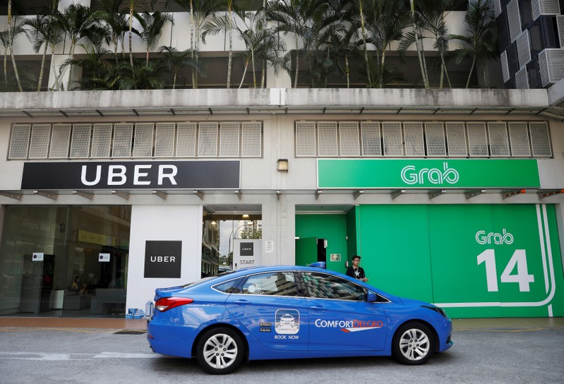 FILE PHOTO: A ComfortDelgro taxi passes Uber and Grab offices in Singapore