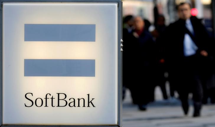 FILE PHOTO: People walk behind the logo of SoftBank Corp in Tokyo
