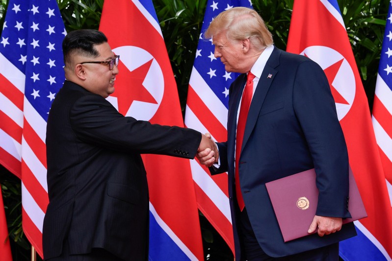 FILE PHOTO - U.S. President Donald Trump and North Korea's leader Kim Jong Un shake hands during the signing of a document after their summit at the Capella Hotel on Sentosa island in Singapore