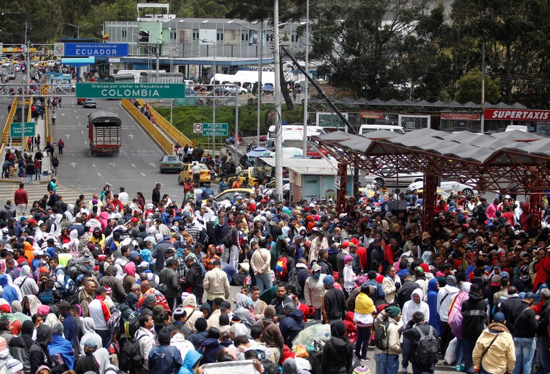 Venezuelan migrants stand in line to register their exit from Colombia before entering into Ecuador, at the Rumichaca International Bridge