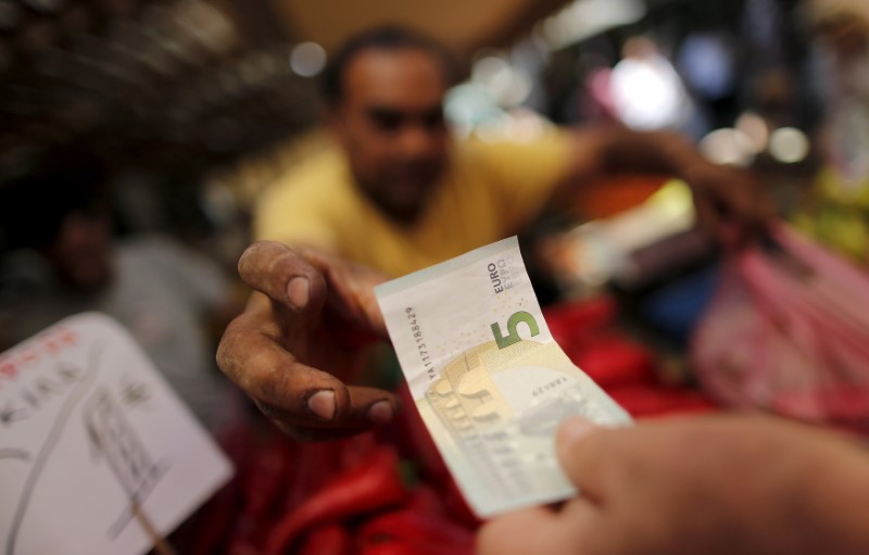 A vendor gets a five Euro bank note from a customer at the central market in Athens