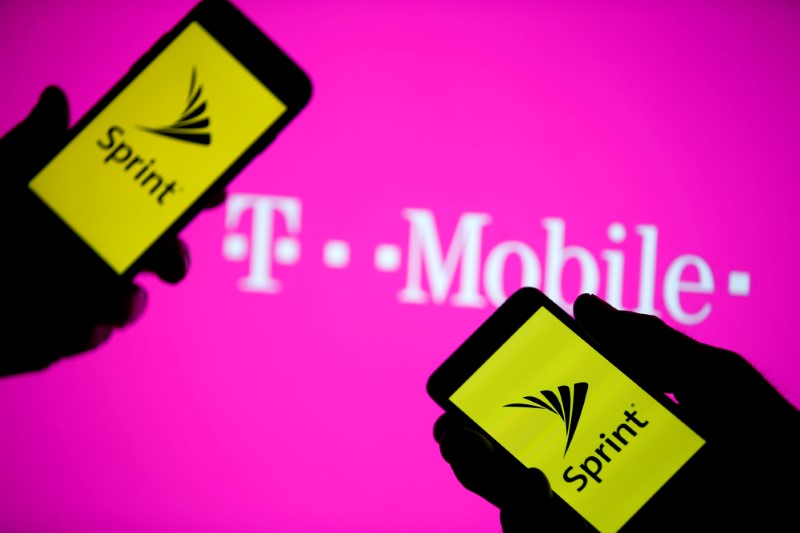 Sprint logo are seen in front of a screen projection of T-mobile logo in this