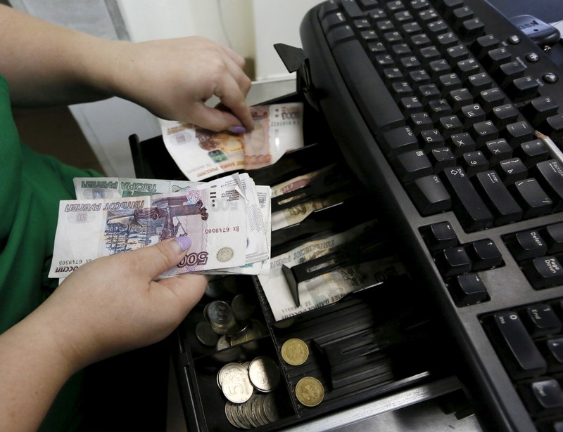 A vendor places Russian rouble banknotes at a grocery shop in Krasnoyarsk