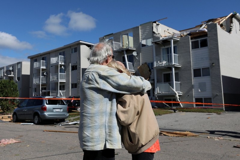 Residents embrace while looking at the damage after a tornado hit the Mont Bleu neighbourhood in Gatineau