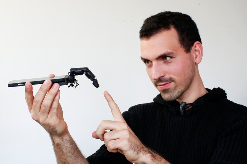 Marc Teyssier, PhD student at Telecom Paris Tech Engineering school, poses with his robot finger 'MobiLimb', that attaches to a mobile phone, after an interview with Reuters in Paris