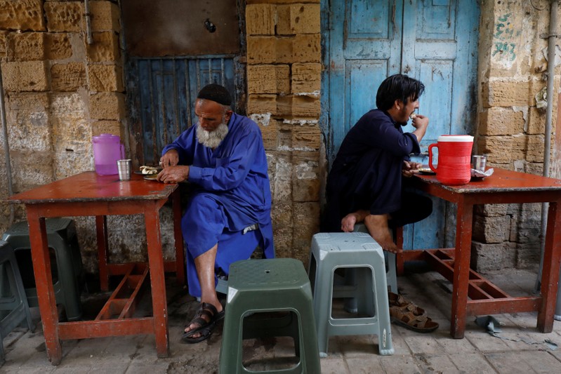 Laborer eat their lunch at a makeshift stall along a sidewalk in Karachi,