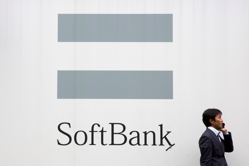 FILE PHOTO : A man talks on the phone as he stand in front of an advertising poster of the SoftBank telecommunications company in Tokyo