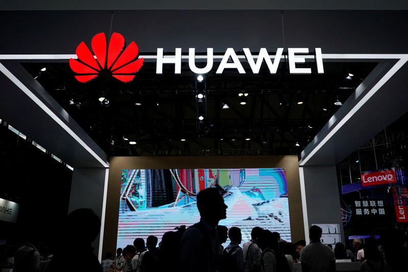 People walk past a sign board of Huawei at CES (Consumer Electronics Show) Asia 2018 in Shanghai