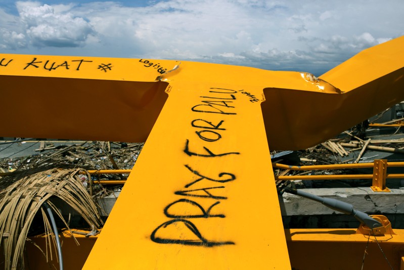 A collapsed bridge with graffiti is seen in Palu
