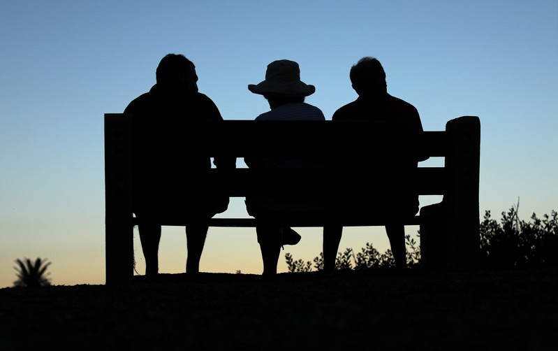 Elderly people sit on a park bench after sun set in Encinitas
