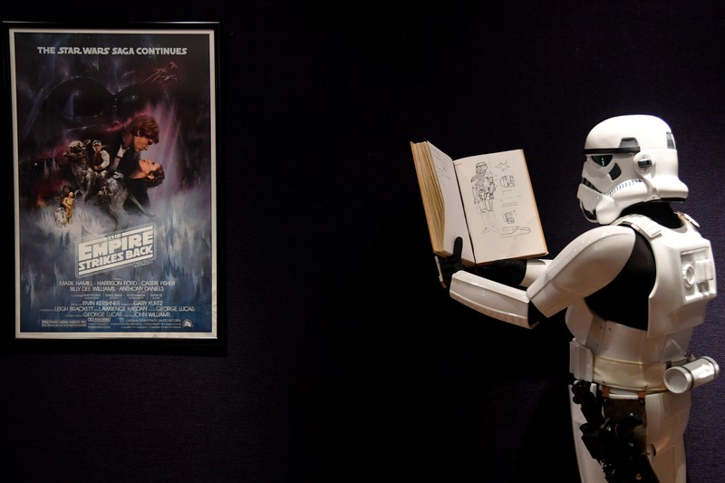 A man wearing a storm trooper costume stands in front of a Star Wars poster belonging to costume designer John Mollo, during a photo-call ahead of an auction at Bonhams in central London