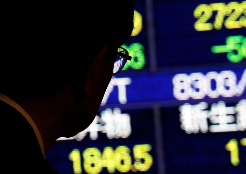 A man looks at an electronic stock quotation board outside a brokerage in Tokyo