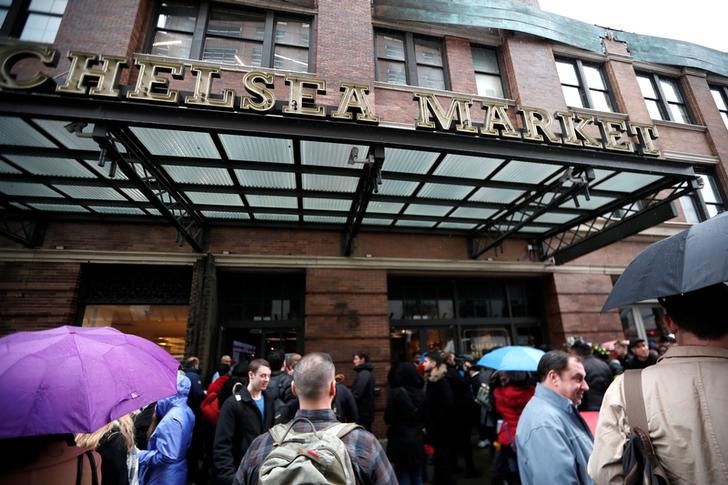 People stand outside the Chelsea Market after it was evacuated due to a rooftop fire in New York City