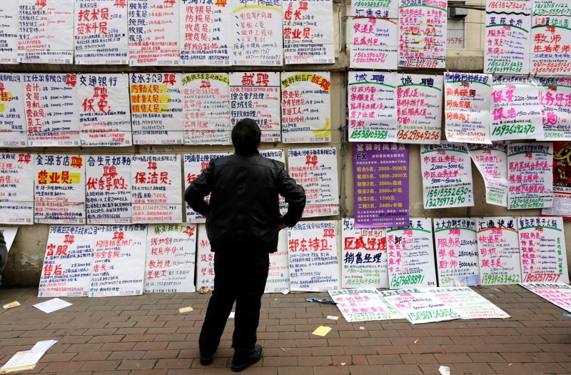 A man looks at job information at an employment fair beside a street in Zhengzhou
