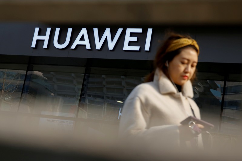 FILE PHOTO: A woman walks past a Huawei shop in Beijing