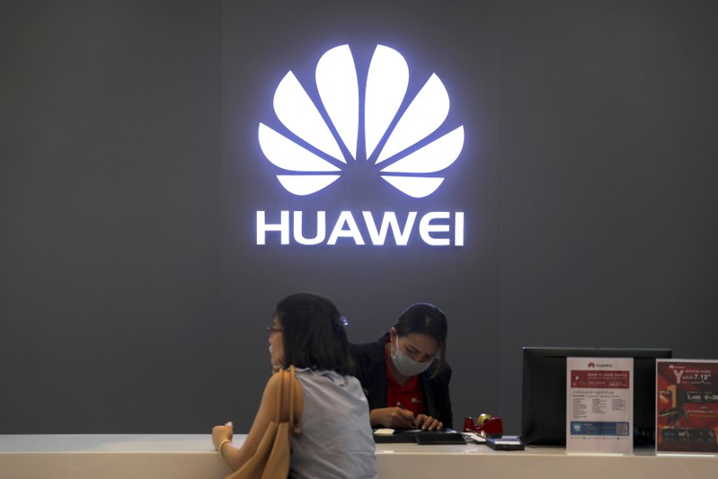 A woman sits next to a salesperson at a Huawei shop in Bangkok, Thailand