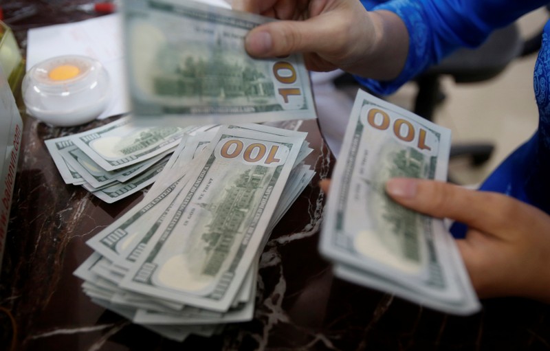 An employee of a bank counts US dollar notes at a branch in Hanoi