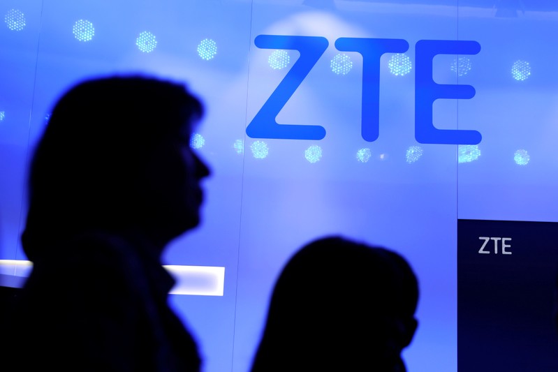 FILE PHOTO: People walk past a ZTE logo outside its booth at the Mobile World Congress in Barcelona