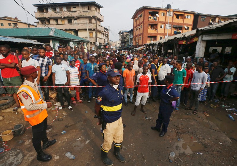 People gather outside a cordoned off area at the site of a collapsed building containing a school in Nigeria's commercial capital of Lagos