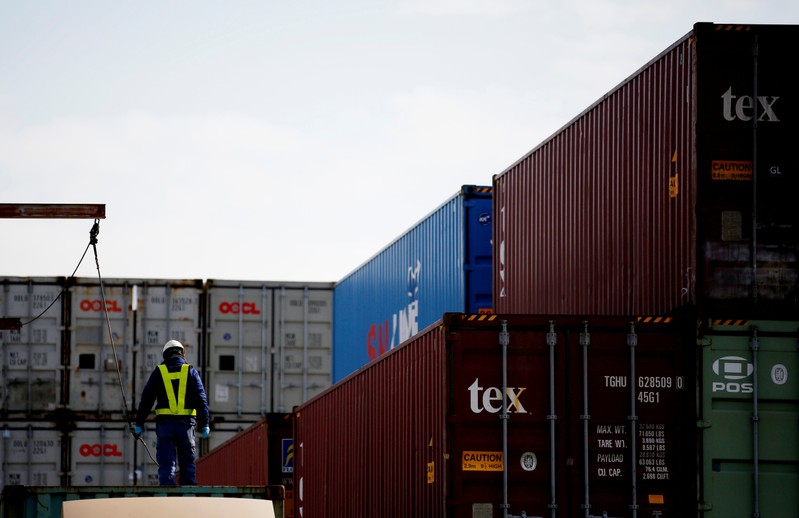 A man works to load a container on a truck at an industrial port in Tokyo