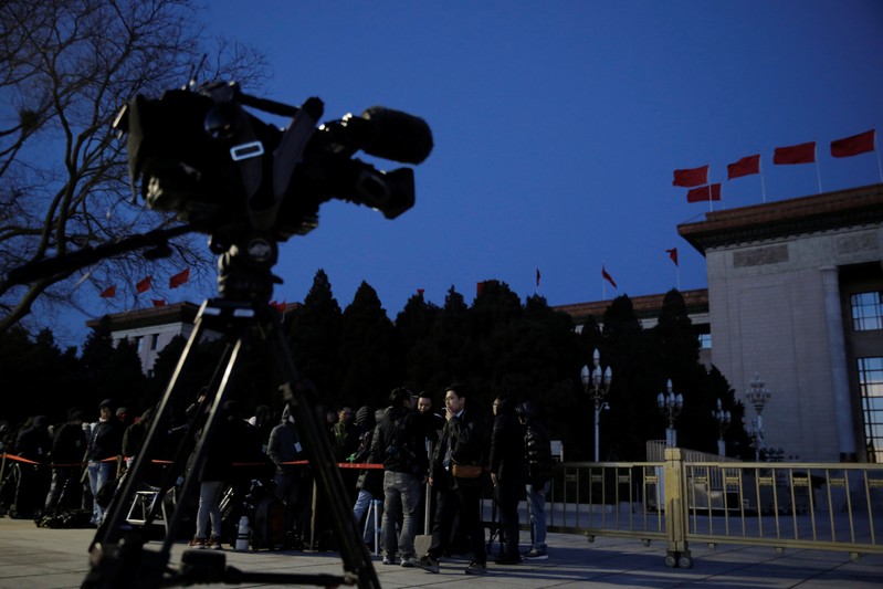 Members of the media line up outside the Great Hall of the People before dawn, ahead of the closing session of the National People's Congress (NPC) in Beijing