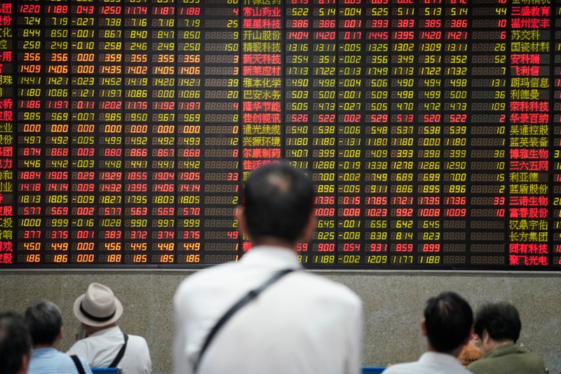 FILE PHOTO: People look at an electronic board showing stock information at a brokerage house in Shanghai